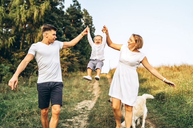 De jonge gelukkige familie met hond heeft pret openlucht