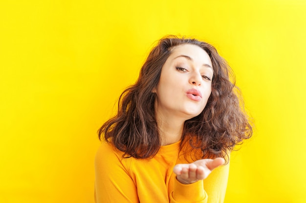 De jonge gelukkige vrouw van het schoonheidsportret op gele geïsoleerde achtergrond