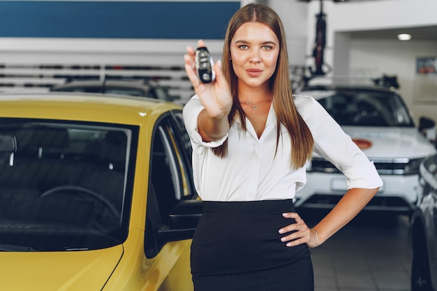 De jonge gelukkige vrouwenkoper / verkoper dichtbij de auto met in hand sleutels sluit omhoog