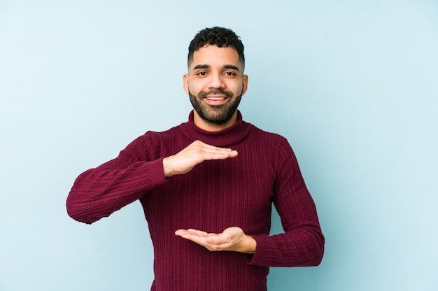 De jonge gemengde ras Arabische mens isoleerde het houden van iets met beide handen, productpresentatie.