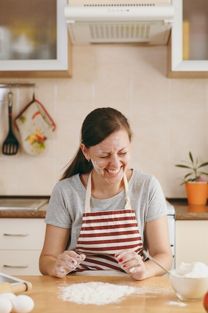 De jonge grappige vrolijke vrouw zit aan een tafel met bloem en gaat een taart in de keuken bereiden. thuis koken. eten koken.