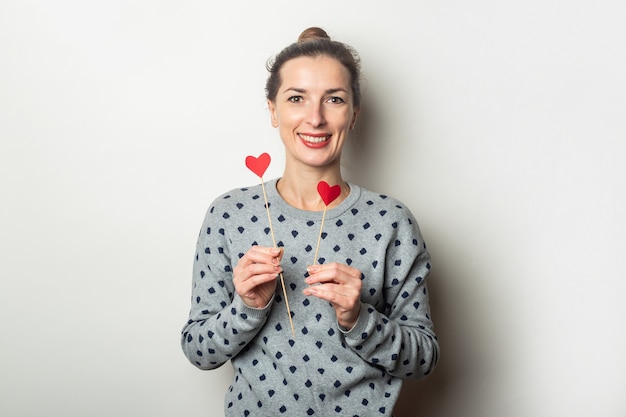 De jonge harten van de vrouwenholding op stokken op een lichte achtergrond. Valentijnsdag, verjaardag. Banner.