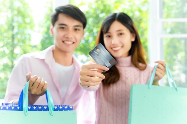 Foto de jonge het winkelen zak van de paarholding en toont creditcard