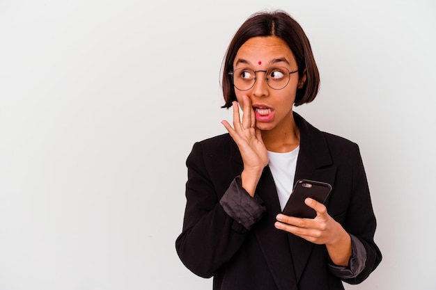 De jonge Indische bedrijfsvrouw die een geïsoleerde telefoon houdt, zegt een geheim heet remmend nieuws en kijkt opzij