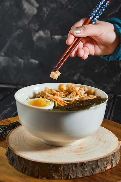 De jonge Japanse vrouw die aan het eten is, smaakt heerlijke udon ramen - Japanse ramen-soep met kip