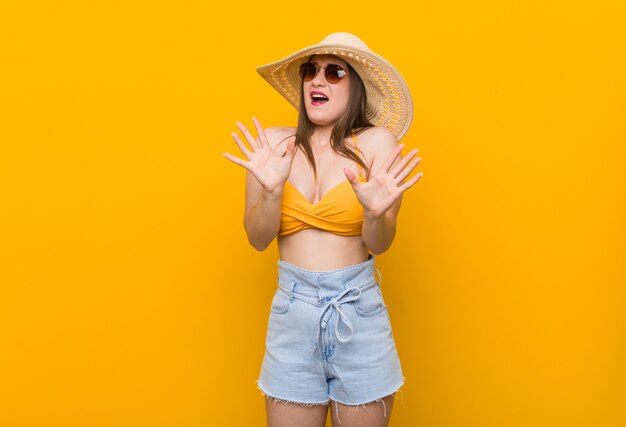 De jonge Kaukasische vrouw die een strohoed, de zomer draagt kijkt verwerpend iemand die een gebaar van afschuw tonen.