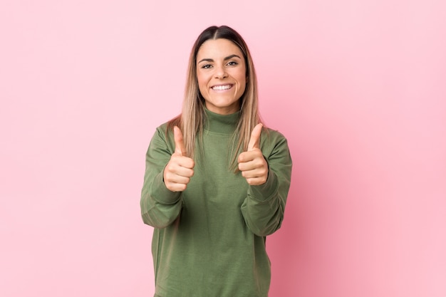 De jonge kaukasische vrouw die met duimen ups wordt geïsoleerd, juicht over iets, steun en eerbiedconcept toe.