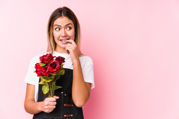 Foto de jonge kaukasische vrouw die rozen houden ontspande het denken over iets bekijkend een lege ruimte.