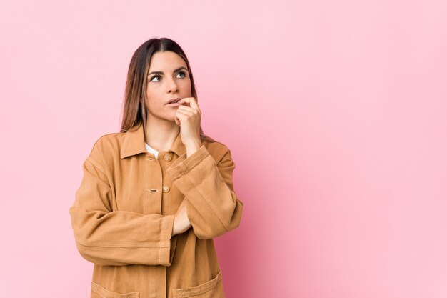 De jonge Kaukasische vrouw isoleerde ontspannen denkend aan iets bekijkend een exemplaarruimte.