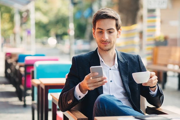 De jonge knappe mens geniet van koffie terwijl het texting