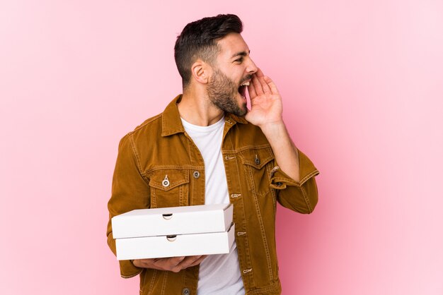 De jonge knappe pizza's van de mensenholding geïsoleerd schreeuwend en houdend palm dichtbij geopende mond.