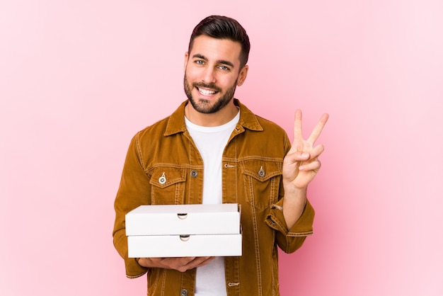 De jonge knappe pizza's van de mensenholding geïsoleerd tonend nummer twee met vingers.