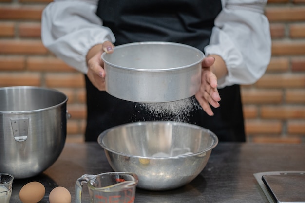 De jonge kokende cake van de vrouwenchef-kok in keuken