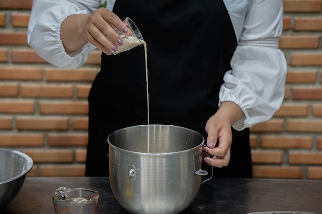 De jonge kokende cake van de vrouwenchef-kok in keuken