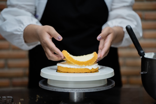 De jonge kokende cake van de vrouwenchef-kok in keuken