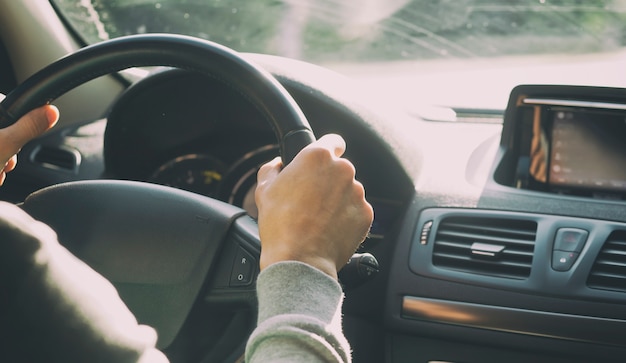 De jonge man besturen van de moderne auto op asfaltweg