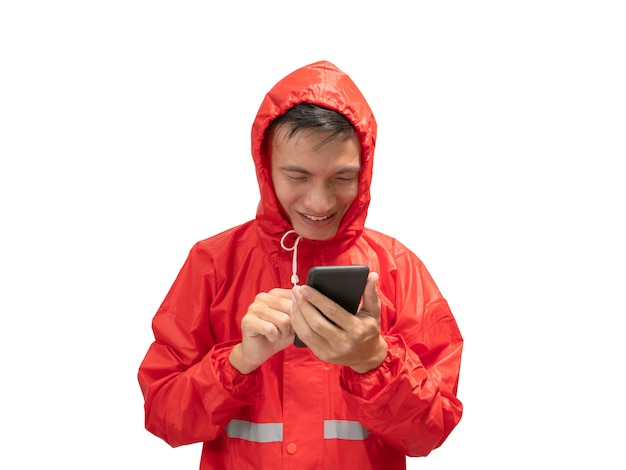 De jonge man draagt ​​een rode regenjas en houdt regenboogkleur van paraplu