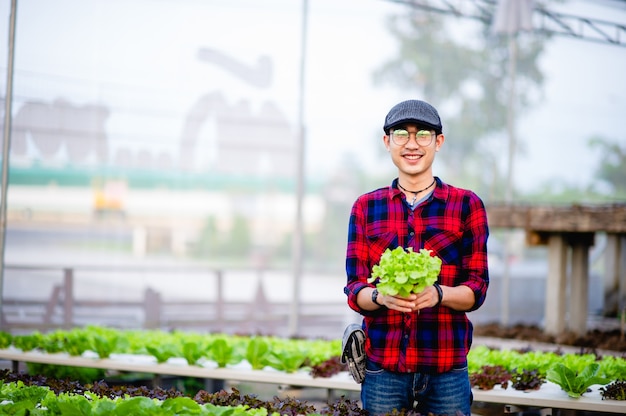 De jonge man en zijn saladetuin en zijn gelukkige glimlach