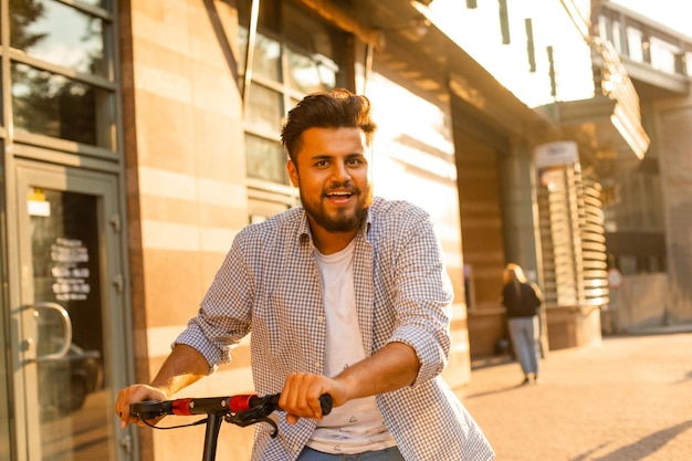 De jonge man heeft een goed humeur terwijl hij op een elektrische scooter rijdt?
