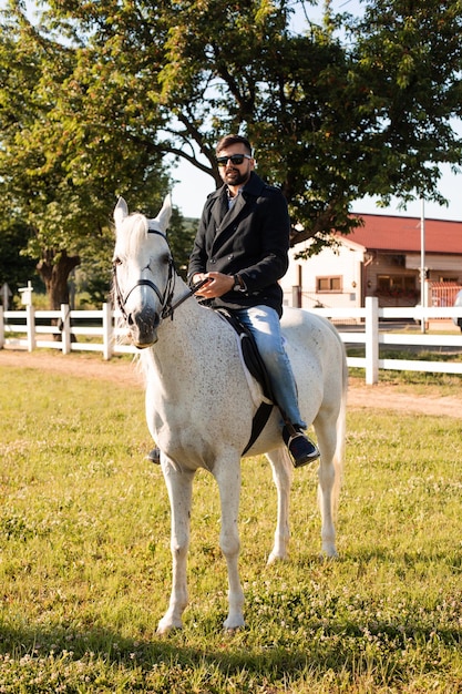 De jonge man rijdt op een paard op een boerderij