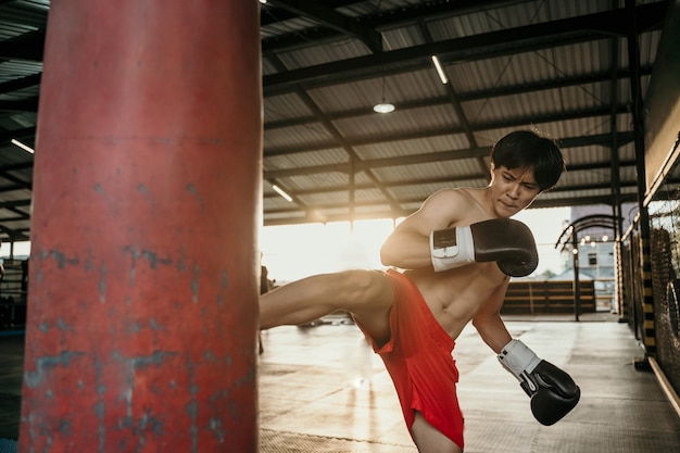 De jonge man traint een kick op de bokszak in de sportschool