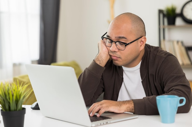 De jonge man werkte voor de laptop, hij was moe en viel in slaap op het bureau