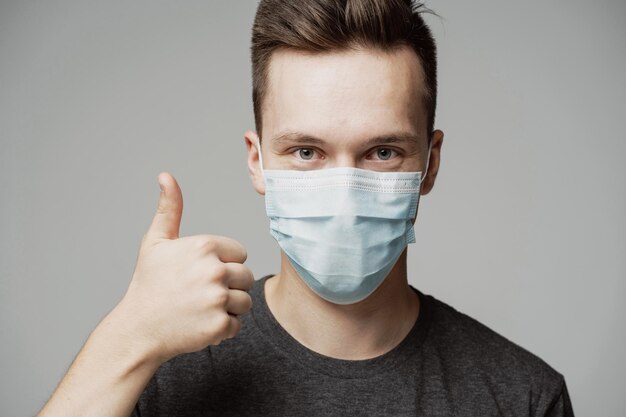 De jonge man wijst met zijn vinger naar de bovenkant een gebaar goed cool portret van een man met een blauw masker