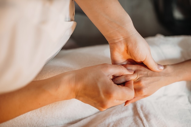 De jonge masseur masseert de vingers van de vrouw om ze te ontspannen na spa-sessies