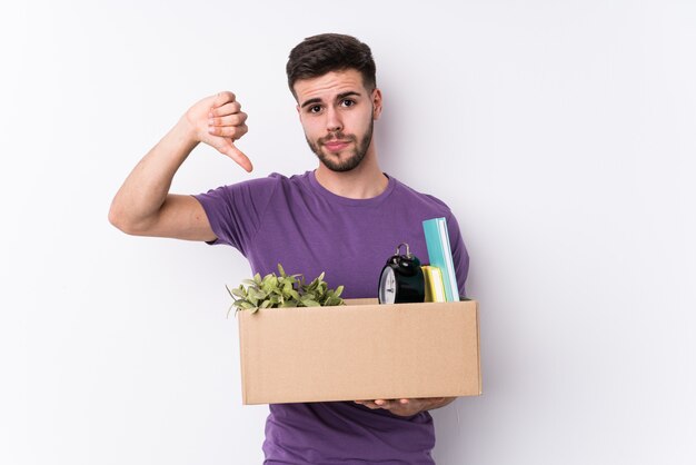 De jonge mens die een nieuw huis beweegt isoleerde neer het tonen van een afkeergebaar, duimen