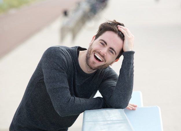 De jonge mens die lacht met dient haar in