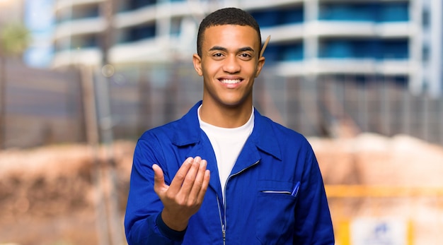 De jonge mens die van de afro Amerikaanse arbeider met hand uitnodigt te komen.