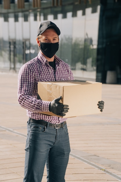 De jonge mens in een medisch masker en handschoenen houdt een document vakje met documenten