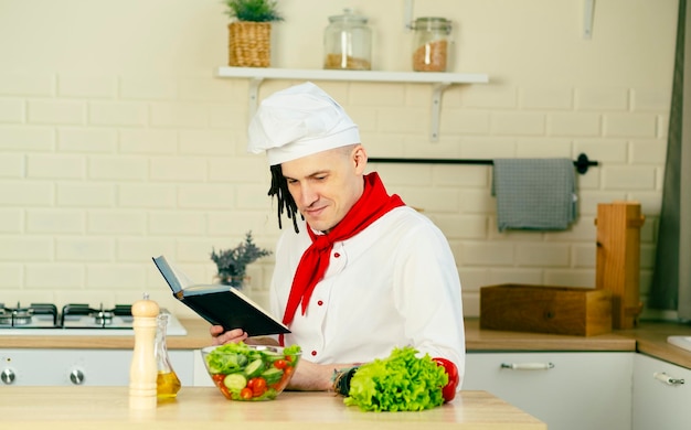 De jonge mens kleedde zich als het receptenboek van de chef-koklezing in keuken Concept voedsel kokende recepten