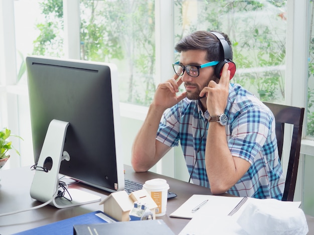 De jonge mens ontspant thuis met oortelefoon