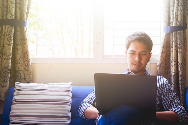 De jonge mens ontspant thuis met sociale media verbinding op laptop computer