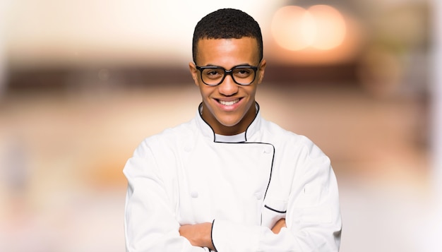 De jonge mens van de afro Amerikaanse chef-kok met glazen en gelukkig unfocused achtergrond