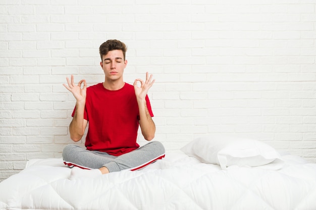 De jonge mens van de tienerstudent op het bed ontspant na harde werkdag, voert zij yoga uit.