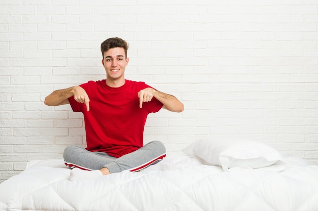 De jonge mens van de tienerstudent op het bed wijst neer met vingers