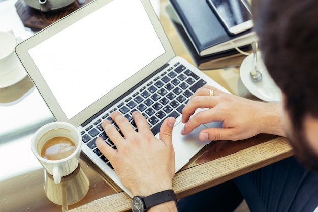 De jonge mens voert werk aan laptop uit