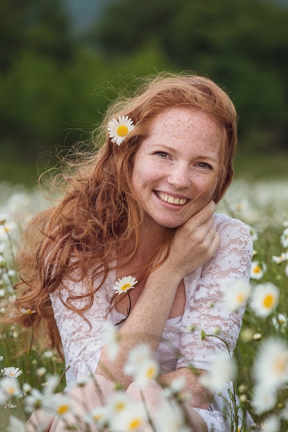 De jonge mooie glimlachende vrouw is op bloem, tearing bloemblaadjes, close-up benieuwd.