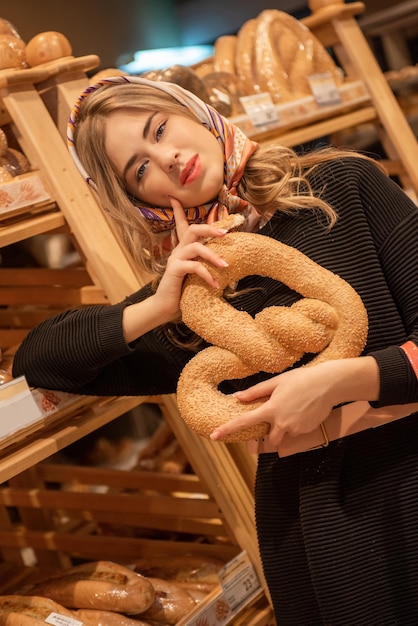 De jonge mooie vrouw in de broodafdeling van de supermarkt