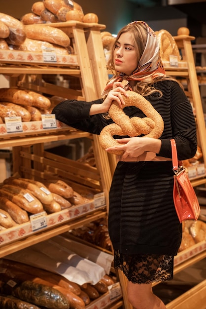 De jonge mooie vrouw in de broodafdeling van de supermarkt