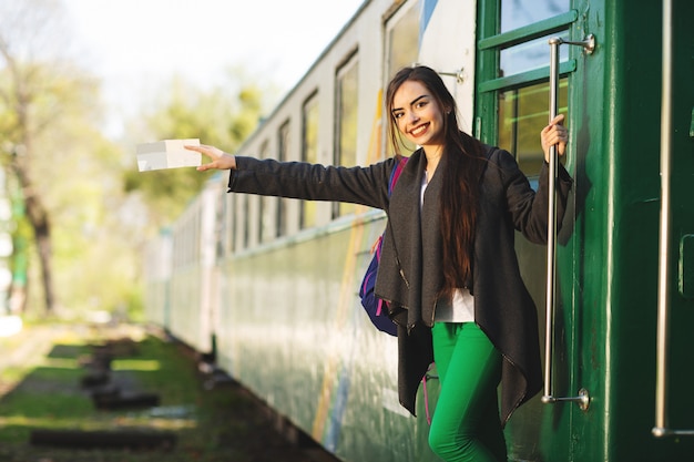 De jonge mooie vrouw met rugzak gaat door trein bij het station reizen.