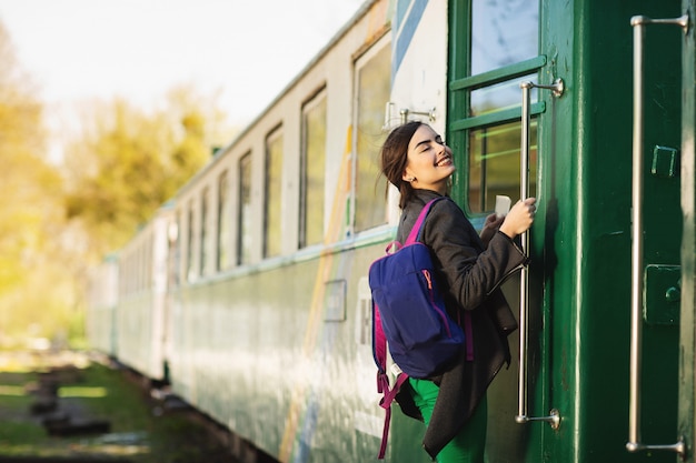 De jonge mooie vrouw met rugzak gaat door trein bij het station reizen.