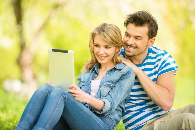 De jonge mooie vrouw zit in hout met tablet.