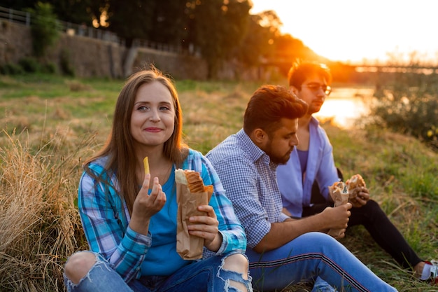 De jonge multi-etnische studenten die fastfood eten op de campus