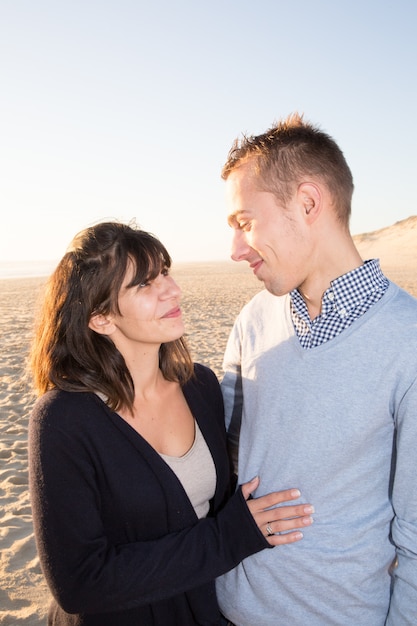 De jonge paarman en de vrouw kijken elkaar op liefde op oceaanstrand