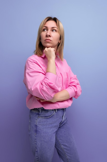 De jonge peinzende blonde kaukasische secretaressevrouw met stromend haar is gekleed in een roze blouse en