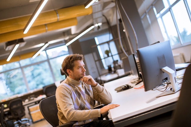 De jonge professionele zakenman gebruikt laptop voor het werk op kantoor