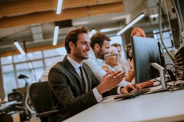 De jonge professionele zakenman gebruikt laptop voor het werk op kantoor